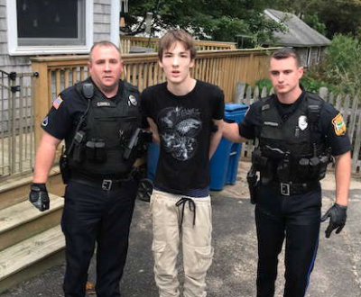 Officers Christopher Corner and Stephen Harrison lead Domenic Albanese out of a house after his arrest. Albanese is being accused of making multiple bomb and “swatting” threats over the past year and a half, including one that prompted a massive law enforcement response at Wareham schools last summer. Photo courtesy: Wareham Police Department