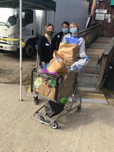 Volunteers prepare to roll a carriage of food out to a family at Damien’s food pantry. From left to right: Ava Johnson, Michele Hanson and Jenna Hanson.