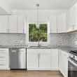 Renovated kitchen with white cabinets, granite counters, a tile backsplash and a gas range at 226 Sanford Road, Westport