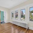 Unit 1 front room with a row of windows, a radiator and hardwood floors at 370 Maple Street, New Bedford