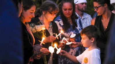Amy Nadolny's son, Joshua Veary, 7, passes a flame between candles of family members and longtime friends during the vigil for Nadolny, Saturday, Oct. 4. Photos by Sam Tucker