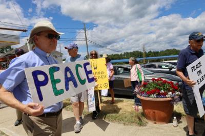 Reverend Daniel Bernier of the Church of the Good Shepherd holds up a sign for peace