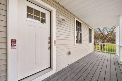 Covered front porch with a white entry door and gray decking at 441 Old County Road in Westport, MA, recently sold