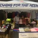 Volunteers stand at the Fishing for the Mission tent.