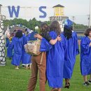 A graduate hugs their friend as they head away from the graduation. 