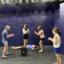 Five young women act out a scene on stage in a class