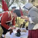 The event had people dressed in historic clothing and offering traditional activities. One booth had historic clothing and jewelry that attendants could buy, while another offered food of the time, like molasses cookies. This booth, led by Cathy Potter, allowed participants to try writing with a feather and ink.